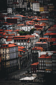 Porto, Portugal - 17. Juni 2022: Blick auf Terrakotta-Dächer, die den Hang hinunterfallen, unterbrochen von den hellen Fassaden der Gebäude im Stadtteil Ribeira, unter einem gedämpften Himmel.