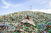 Chittagong, Bangladesh - 22 September 2022: View of a young boy amidst a massive, overwhelming mountain of discarded plastic bottles under a vast, expansive sky.