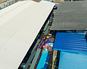 Luftaufnahme von Booten, die durch die belebten Wasserstraßen fahren, ein lebendiger Teppich aus bunten Schirmen und traditionellem thailändischem Handel, Damnoen Saduak, Thailand.
