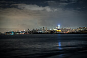 View of the city lights twinkling against the dark water and sky, creating a mesmerizing contrast of illumination and shadow, San Francisco, California, United States.