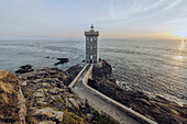 View of the Kermorvan Lighthouse stands tall against the setting sun, its stone facade a beacon of maritime history, Route de la Presqu'île Kermorvan, Le Conquet, Bretagne, France.