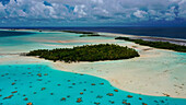 Aerial view of turquoise waters embrace lush, verdant islands under a sky brushed with clouds, a tropical haven's serene beauty, French Polynesia.