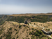 Luftaufnahme der Vahramashen-Kirche auf einem sonnenverbrannten Bergrücken, deren alte Steine sich von den ockerfarbenen Wiesen abheben, Vahramashen-Kirche, Provinz Aragatsotn, Armenien.