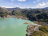 Luftaufnahme von türkisblauem Wasser und zerklüftetem, felsigem Gelände unter einem weiten Himmel, wo sich die raue Schönheit der Natur in einer Symphonie von Strukturen und Farben entfaltet, Bladalsvatnet, Matre, Vestland, Norwegen.