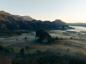 Aerial view of a mystical landscape shrouded in ethereal mist with rugged mountains piercing through the clouds, Phu Langka Forest Park, Pha Chang Noi, Thailand.