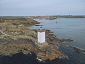 Aerial view of Phare de Kermorvan's stark white tower stands sentinel against the rugged coastline, where the rocks meet the serene sea, Le Conquet, Bretagne, France.