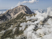 Luftaufnahme des majestätischen Gran Sasso, der durch ein Meer aus ätherischen Wolken sticht, Campo Imperatore, Abruzzen, Italien.