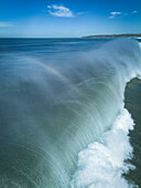 Luftaufnahme einer kolossalen, sich kräuselnden und krachenden Welle, deren schäumender Kamm im Kontrast zum tiefblauen Meer steht, Dixon Park, Newcastle, Australien.
