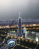 Aerial view of the sleek, modern architecture of the Batumi Resort, contrasting against the serene coastline and the city lights twinkling below, Batumi, Adjara, Georgia.