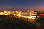 Aerial view of the architecturally striking Stazione AV Mediopadana glows against the twilight sky, its sleek lines cutting through the landscape, Stazione AV Mediopadana, Emilia-Romagna, Italy.