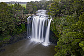 Luftaufnahme des majestätischen, kaskadenförmig in das dunkle Becken darunter stürzenden Wasserfalls, umrahmt von einem üppig grünen Walddach, Kerikeri, Region Northland, Neuseeland.
