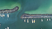 Luftaufnahme von Booten, die im Hafen liegen. Die dunklen Wellenbrecher kontrastieren mit dem türkisfarbenen Wasser und schaffen eine ruhige Szene, Portland, Victoria, Australien.