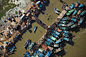 Aerial view of vibrant boats clustered around the pier, bustling with activity under the bright sun, a lively scene of river life, Yanam, Puducherry, India.
