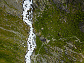 Aerial view of a raging river cutting through verdant slopes, showcasing nature's raw power and serene beauty, Buarbreen, Odda, Norway.