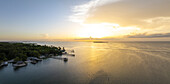 Aerial view of the radiant sun kissing the tranquil waters near the coastline and docks, casting a golden glow over the landscape, Key Largo, Florida, United States.