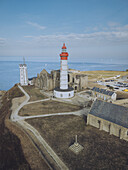 Aerial view of the majestic Saint-Mathieu Lighthouse, its red and white stripes a stark contrast against the azure sea and the ancient abbey ruins, Plougonvelin, Bretagne, France.