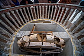 View of an old rusty, bucket-wheel mechanism within a stone structure, observed from an ornate marble railing above, Kartarpur, Punjab, Pakistan.