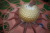 Aerial view of the golden orb structure contrasts against the red brick and green geometric patterns below, Bommayapalayam, Tamil Nadu, India.