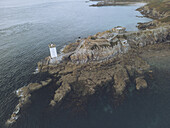 Aerial view of the Phare de Kermorvan lighthouse standing sentinel on rocky outcrop kissed by the Atlantic's waves, Le Conquet, Bretagne, France.