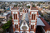 Luftaufnahme der Herz-Jesu-Basilika, deren markante rot-weiße Fassade sich majestätisch inmitten des Stadtbildes erhebt, Puducherry, Puducherry, Indien.