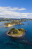 Luftaufnahme der sonnenverwöhnten Inseln inmitten des türkisfarbenen Wassers, ein Küstenparadies, in dem grüne Hügel auf den weiten Ozean treffen, Mahinepua Bay, Te Tai-tokerau, Neuseeland.