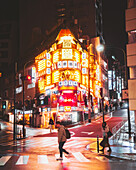 Shibuya, Japan - 05 March 2025: View of the vibrant, glowing corner building in Shibuya, where pedestrians cross the wet street under the electric glow of signs and lights.