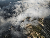 Luftaufnahme der zerklüfteten, in himmlische Wolken gehüllten Gipfel, ein Tanz von Licht und Schatten über dem Gran Sasso-Gebirge, Campo Imperatore, Abruzzen, Italien.