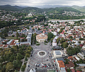 Aerial view of the vibrant heart of the city unfolds with the Meskhishvili Theatre standing as a beacon of culture and history, framed by the distant mountains, Kutaisi, Imereti, Georgia.