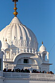 Kartarpur, Pakistan - 09 November 2019: View of the gleaming white dome of Gurdwara Darbar Sahib under a clear blue sky, a beacon of faith and serenity.