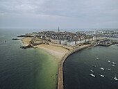 Aerial view of the walled city and beaches of Saint-Malo, where the emerald sea meets the sandy shores under a vast sky., Saint-Malo, Brittany, France.