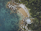 Aerial view of vibrant turquoise waters meet rugged pink granite rocks and lush green vegetation at Ploumanac'h, Perros-Guirec, Bretagne, France.