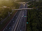 Aerial view of the highway cutting through lush green trees, with cars and trucks moving along the lanes, Charlotte, North Carolina, United States.