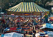 Bogura, Bangladesh - 09 February 2022: Aerial view of a vibrant fair with a striking yellow and blue tent amidst a bustling crowd, creating a lively scene.