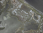 Luftaufnahme von flachen Gewässern, die einen Wandteppich aus erdigen Braun- und Grüntönen bilden, unterteilt durch dünne Landstreifen, Etang de Leucate, Okzitanien, Frankreich.