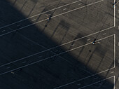 Concord, United States - 28 July 2025: Aerial view of a stark parking lot, shadows stretch diagonally across the asphalt, creating a dramatic contrast with the bright white lines.
