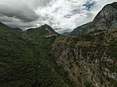 Luftaufnahme der zerklüfteten Berge und des üppigen Tals, ein Wandteppich aus Grün und Braun unter einem dramatischen Himmel, Gole del Sagittario, Anversa degli Abruzzi, Abruzzen, Italien.