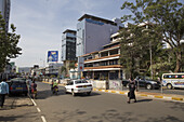 Kisumu, Kenya - 13 May 2021: View of a bustling Kisumu street, where pedestrians and vehicles navigate the vibrant scene against a backdrop of modern buildings and clear sky.