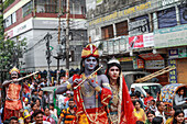 Narayanganj, Bangladesh - 23 August 2019: View of vibrant devotees, adorned in striking costumes, parade through the bustling streets near Trust Bank, celebrating their faith with music and joy.
