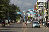Kisumu, Kenya - 13 May 2021: View of the bustling Jomo Kenyatta Highway, where vibrant green trees meet the lively street scene, as pedestrians cross amidst the diverse array of vehicles.