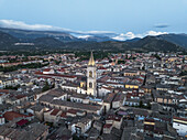 Aerial view of the illuminated spire of the Annunziata complex rises above the ancient rooftops as dusk settles over the valley, Sulmona, Abruzzo, Italy.