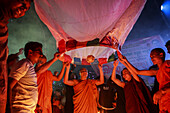 Chattogram, Bangladesch - 09. Oktober 2022: Blick auf Mönche und Kinder, die eine leuchtende Himmelslaterne in die Nacht entlassen, die ein warmes Licht auf die Gesichter wirft.