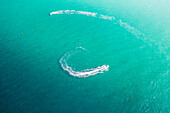 Aerial view of jet skis carve white arcs in the turquoise sea, creating a mesmerizing contrast of motion and color, Miami Beach, Florida, USA.