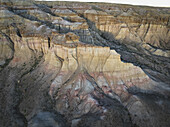 Aerial view of the sun paints the cliffs with warm hues, casting shadows that accentuate the rugged beauty of Tsagaan Suvarga's unique formations, Tsagaan Suvarga, Dundgovi, Mongolia.