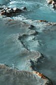 Blick auf türkisfarbenes Wasser, das in Kaskaden über terrassenförmig angelegte Travertinfelsen fließt und ein faszinierendes, natürliches Spa-Erlebnis schafft, Saturnia, Toskana, Italien.