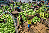Dhaka, Bangladesh - 08 April 2018: View of vibrant watermelons piled high on boats, as men navigate the waterways, their colorful clothing contrasting with the verdant fruit..