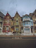 Blick auf lebendige und verzierte Häuser, die Schulter an Schulter unter einem düsteren Himmel stehen, ihre Fassaden sind ein Zeugnis architektonischer Kunstfertigkeit, Mers-les-Bains, Hauts-de-France, Frankreich.
