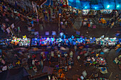 Dhaka, Bangladesh - 13 September 2015: Aerial view of the bustling marketplace in Dhaka, where vibrant blue tarps contrast with the warm glow of streetlights above the crowded stalls.