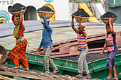 Dhaka, Bangladesh - 14 May 2023: View of laborers carrying baskets of coal, their vibrant clothes contrasting against the dark cargo, a scene of labor against the backdrop of the city.