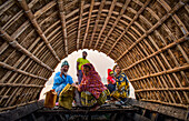 Bogura, Bangladesh - 05 February 2018: View of a family seated inside a traditional wooden boat, the warm light glinting off the water and illuminating the intricate bamboo framework overhead.