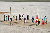 Bogura, Bangladesh - 18 December 2020: View of a spirited volleyball game unfolds on the expansive, sun-baked earth, with vibrant clothing colors contrasting with the parched ground.